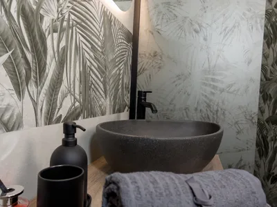 Dettaglio del lavabo in pietra nera con dispenser e accessori coordinati