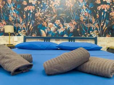 Letto matrimoniale con cuscini blu e asciugamani arrotolati di cortesia