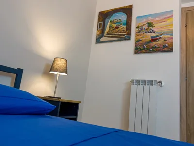 Angolo della camera singola con lampada da comodino e quadri di paesaggi marini siciliani