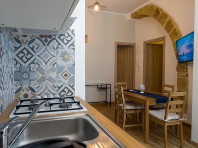 Piano cottura a gas con piastrelle in maiolica decorata, vista sulla zona pranzo e sull'arco in pietra