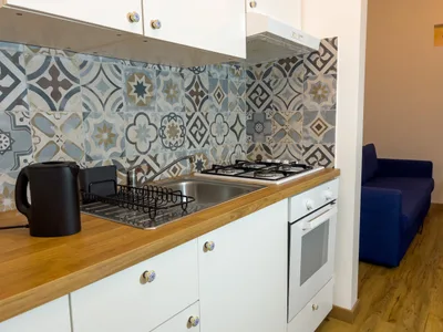 Cucina attrezzata con lavello, piano cottura a gas, forno, bollitore e piastrelle patchwork