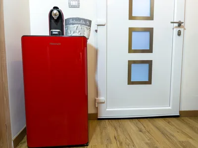 Frigorifero rosso in stile retro con macchina del caffe accanto alla porta d'ingresso