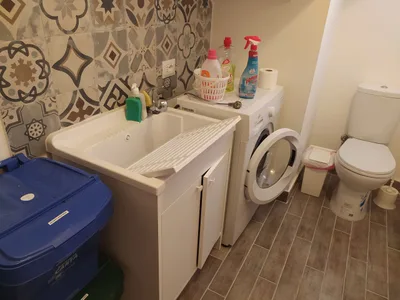 Stanza lavanderia con lavatoio, lavatrice, WC di servizio e contenitori per la raccolta differenziata