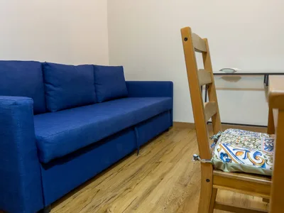 Divano letto blu del soggiorno con sedia in legno e cuscino in maiolica siciliana