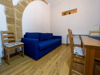 Soggiorno con arco in pietra a vista, divano blu, scrivania e nicchia decorativa illuminata
