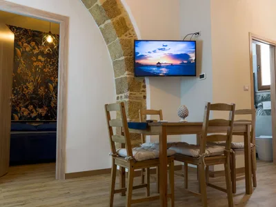 Zona pranzo con TV a parete accanto all'arco in pietra e vista sulla camera matrimoniale